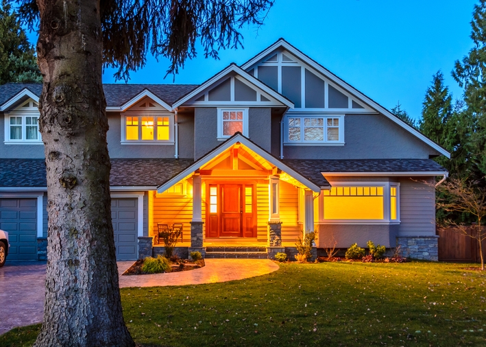 An exterior view of a house with a bright porch light and white windows An exterior view of a house with a bright porch light and white windows
