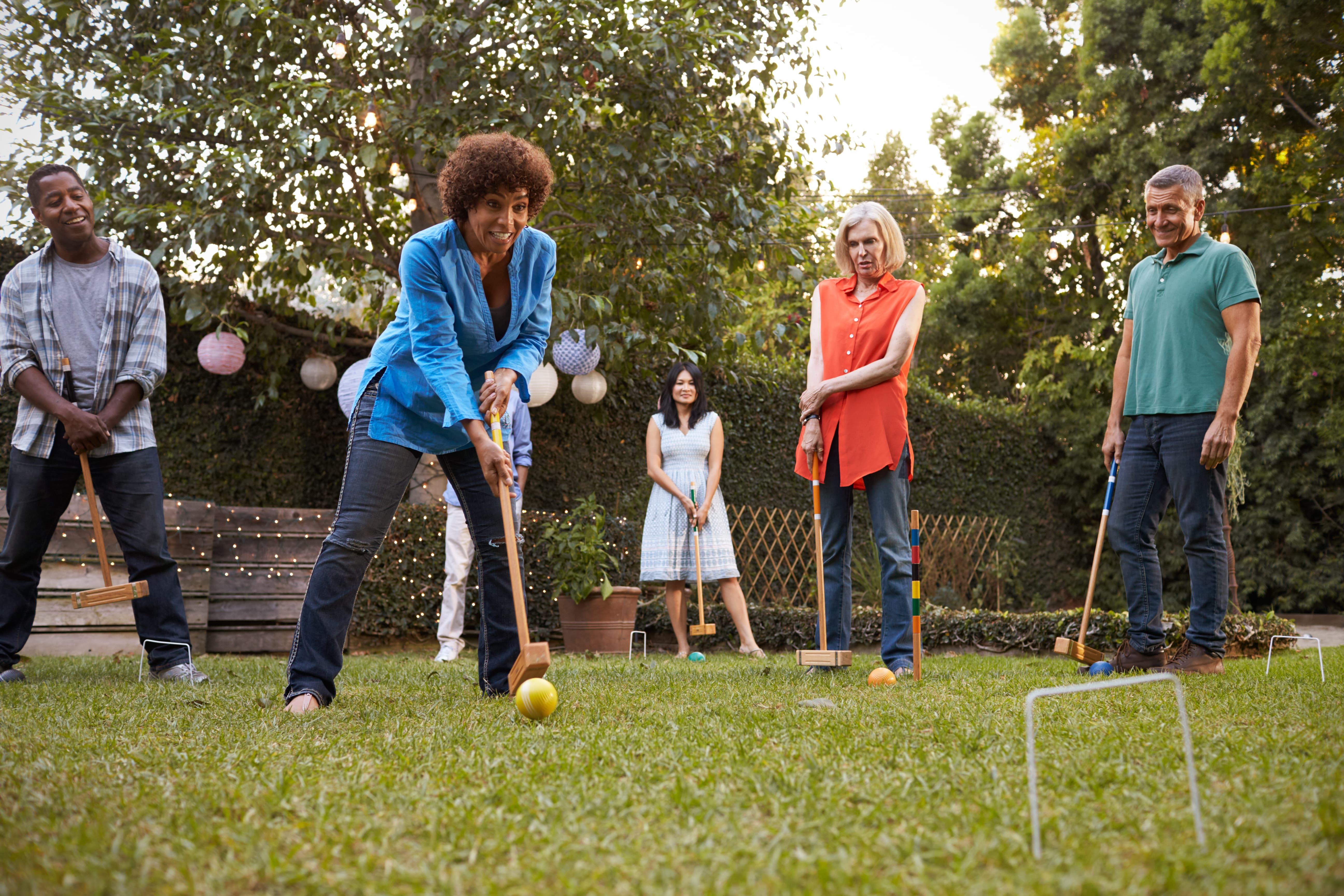 Adults playing croquet in their backyard Adults playing croquet in their backyard