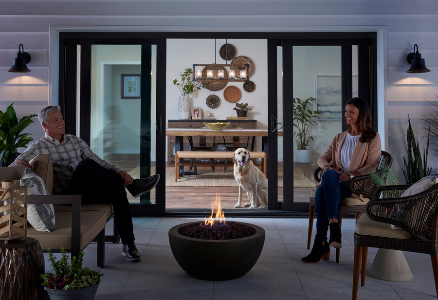 Couple enjoying a fire bowl in front of open sliding glass patio doors Couple enjoying a fire bowl in front of open sliding glass patio doors
