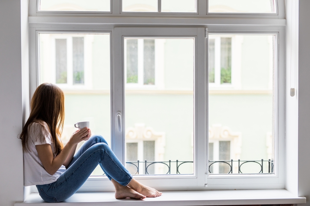 Woman sitting by window with coffee Woman sitting by window with coffee